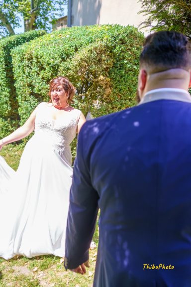 Une mariée en robe blanche se tient dans un jardin, regardant un homme en costume.