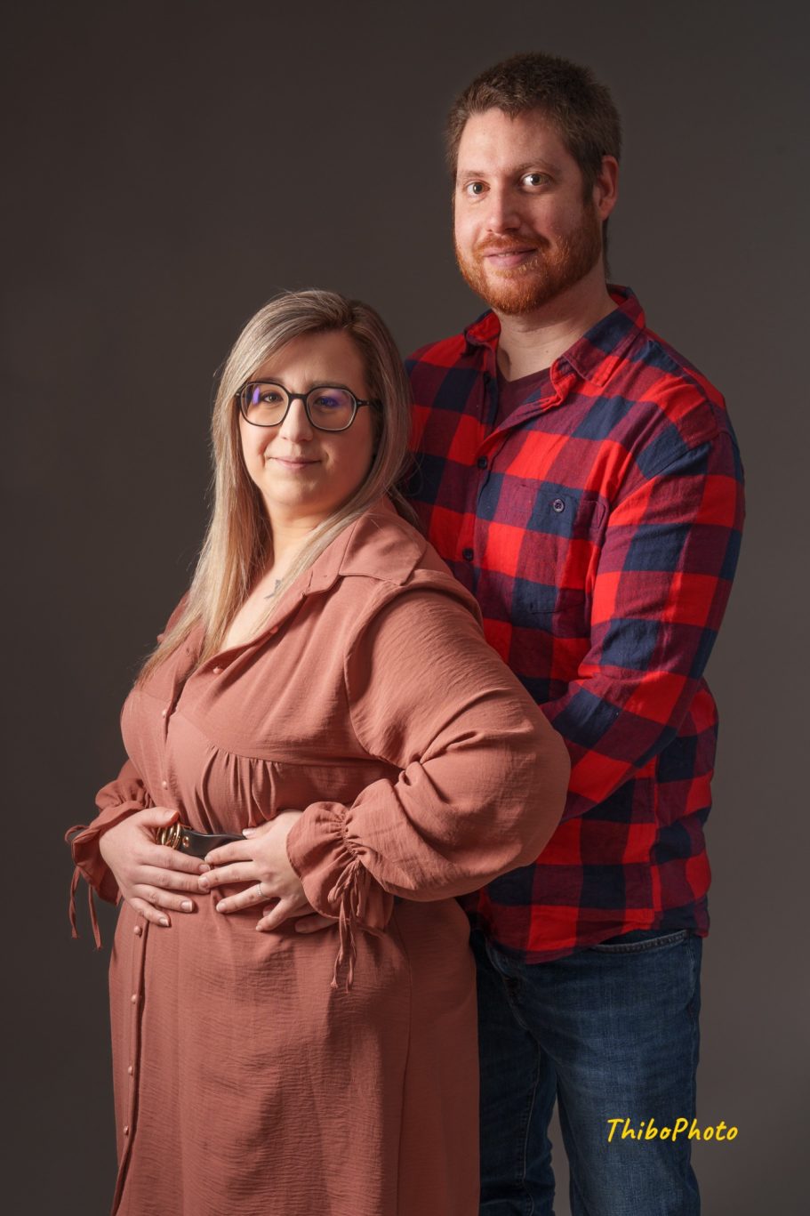 Un couple souriant, elle enceinte, posant ensemble avec affection.
