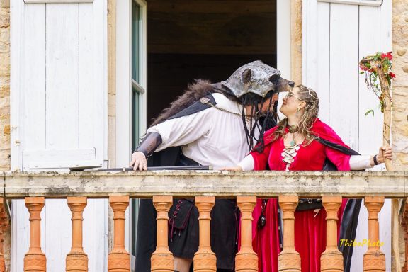 Deux personnes déguisées en personnages médiévaux s'embrassent sur un balcon.