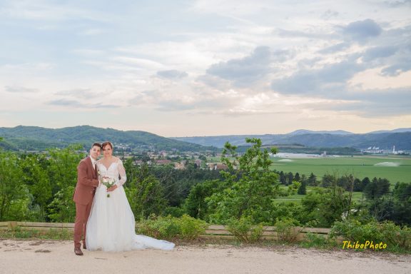 Mariage avec le couple posant en pleine nature, paysage verdoyant en arrière-plan.