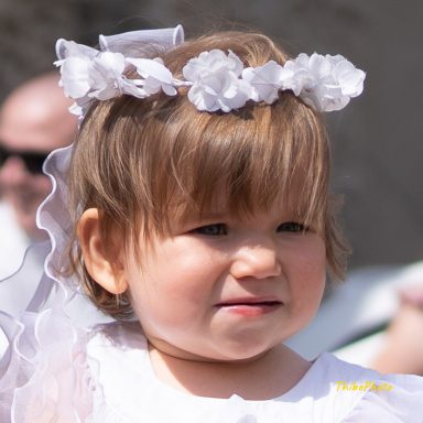 Fille souriante avec une couronne de fleurs blanches et une robe blanche.