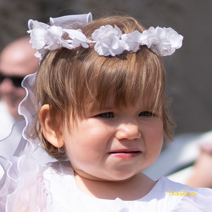 Fille souriante avec une couronne de fleurs blanches et une robe blanche.