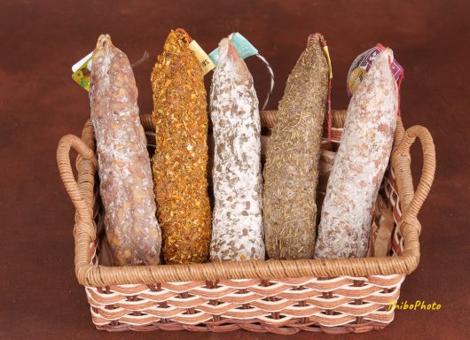 Assortiment de saucissons présentés dans un panier en osier.