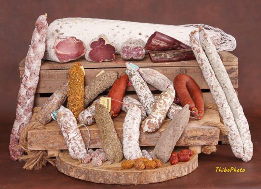 Assortiment de saucissons et viandes séchées sur un plateau en bois.