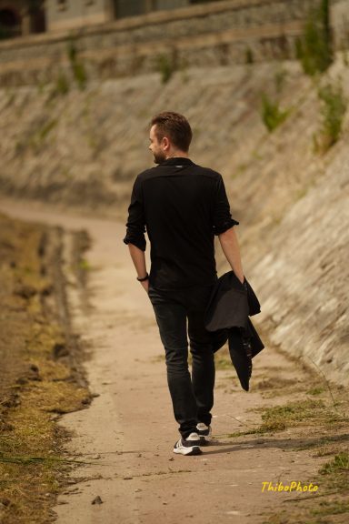 Un homme marchant le long d'un chemin, portant une veste sur l'épaule.
